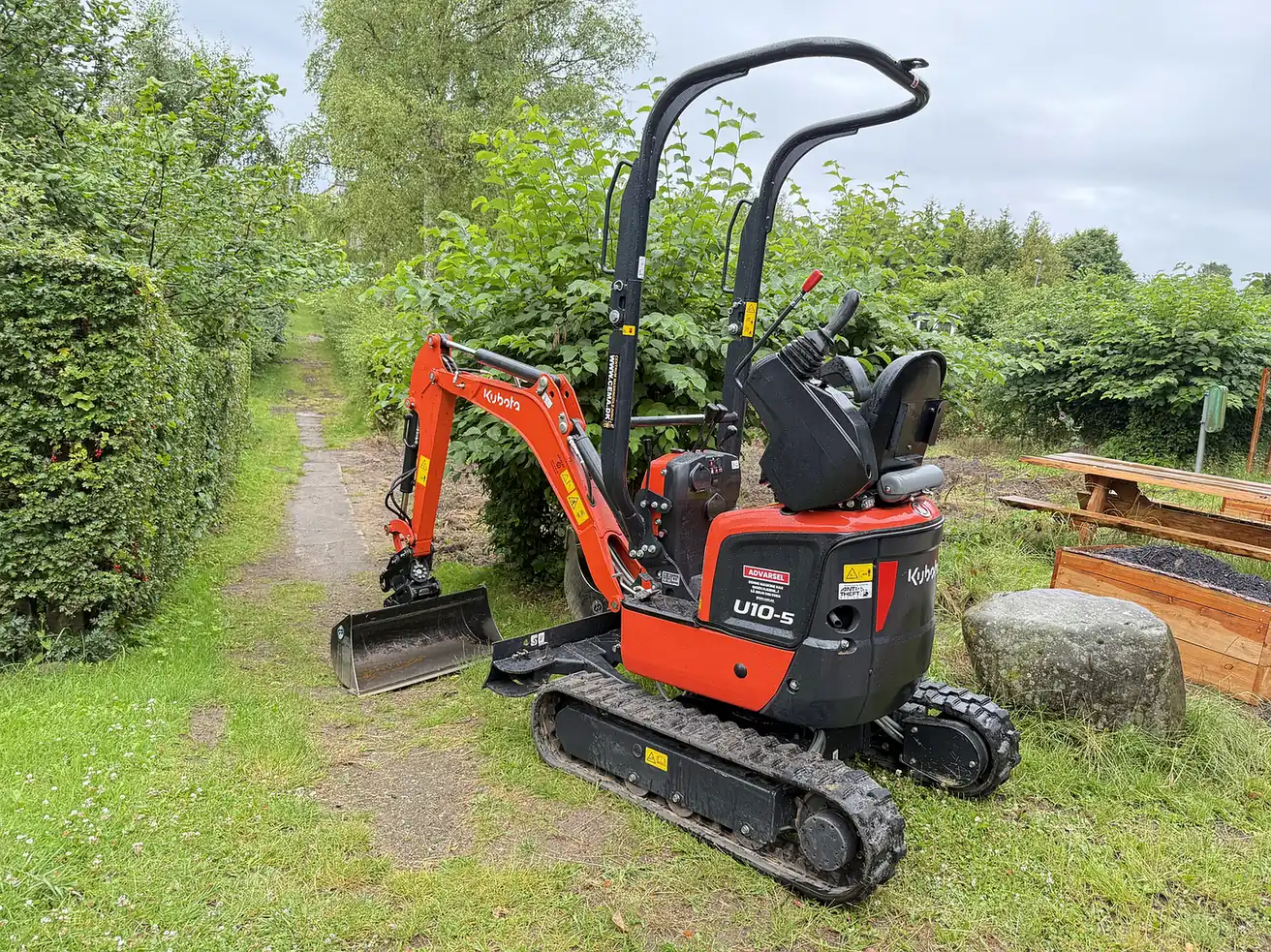 Kubota U10-5 minigraver kører gennem smal hækgang